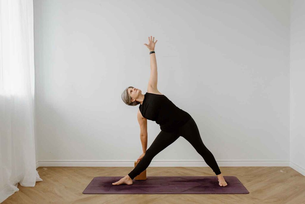 older woman doing a variations of extended triangle yoga pose